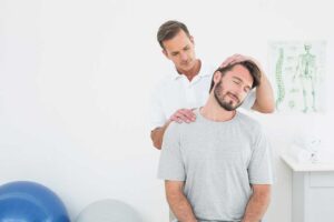 A chiropractor explaining a spinal model to an adult and child in a comfortable clinic setting.