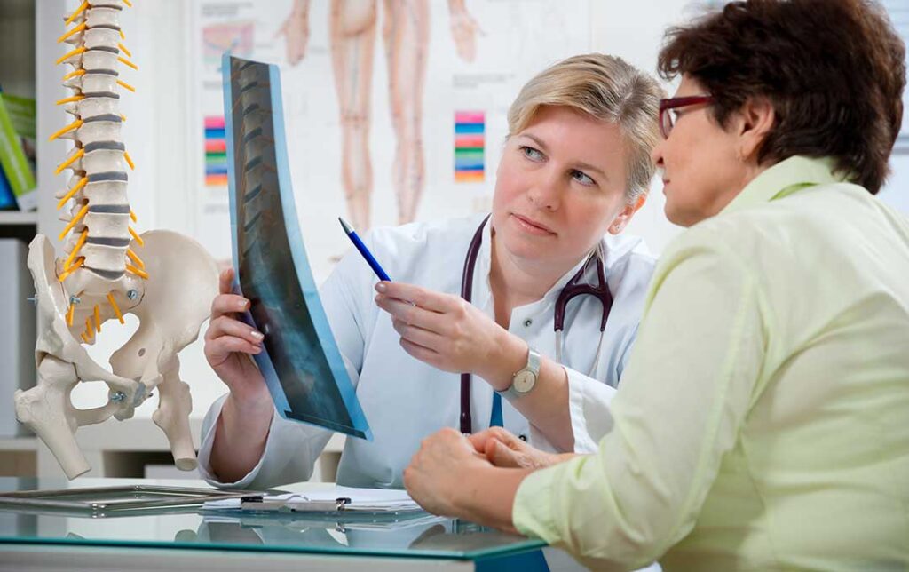Person doing gentle neck exercises beside a desk with an elevated monitor and relaxed shoulders